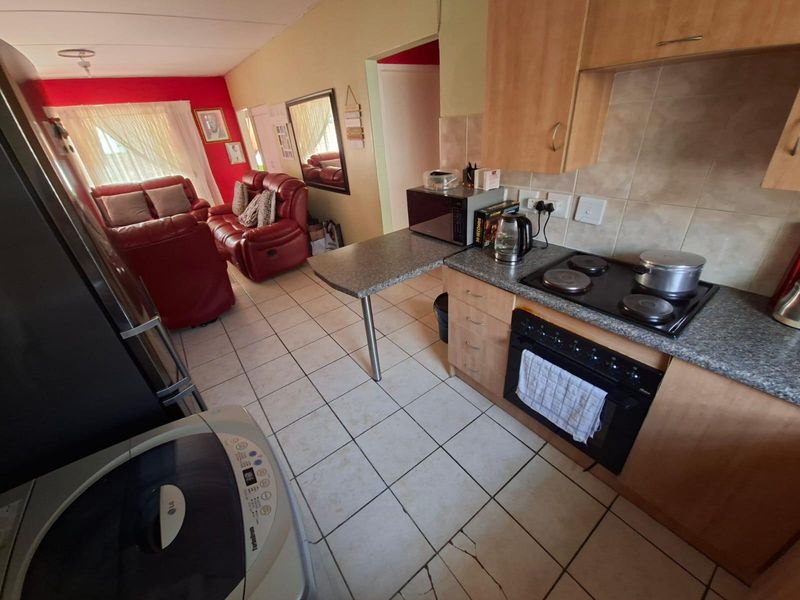 Open-plan kitchen and living area featuring tiled flooring, built-in cabinetry, and an integrated electric hob and oven.