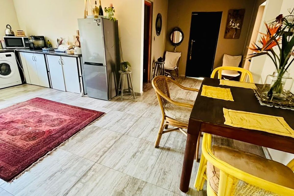 Open-plan living and dining area featuring tiled flooring, recessed lighting, and a functional kitchen layout with built-in cabinetry.
