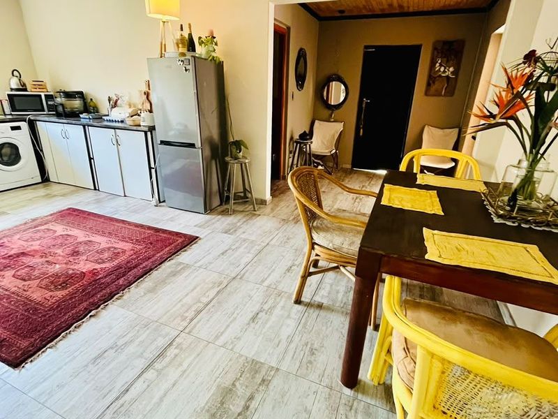 Open-plan living and dining area featuring tiled flooring, recessed lighting, and a functional kitchen layout with built-in cabinetry.