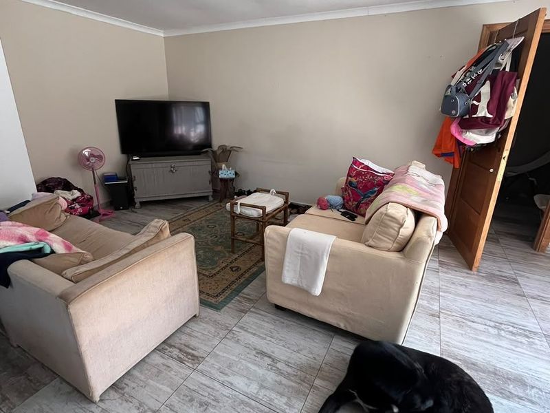 A living room area featuring tiled flooring and coved ceilings, currently showing signs of wear on the walls and ceiling.