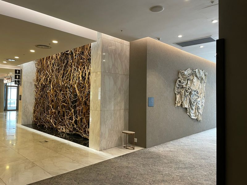 A modern, well-maintained hallway featuring high-end finishes, including marble wall cladding, recessed lighting, and a decorative feature wall.