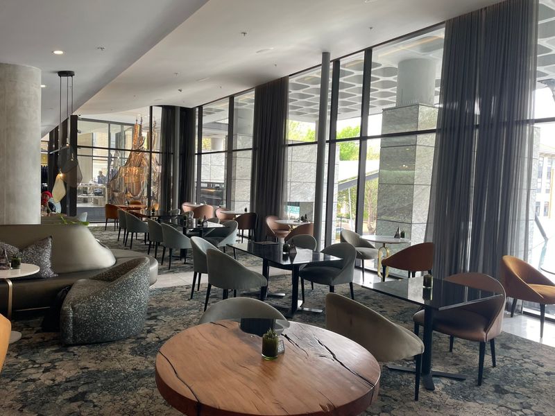 A modern, open-plan living area featuring expansive floor-to-ceiling windows, recessed lighting, and contemporary architectural finishes, creating a bright and sophisticated atmosphere.