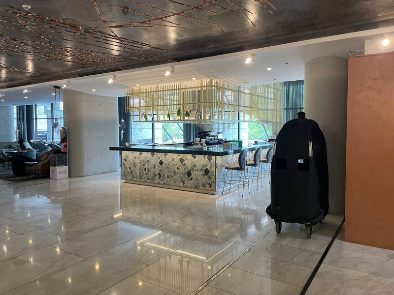 A modern, well-appointed bar area featuring a decorative tiled counter, suspended shelving, and polished marble-look flooring in a contemporary open-plan setting.