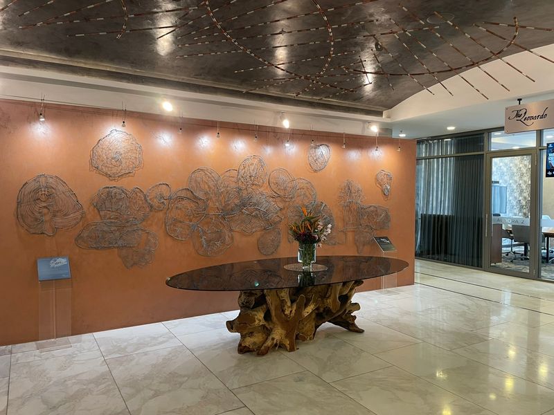 Elegant apartment building entrance lobby featuring polished tiled flooring, a unique decorative ceiling installation, and a feature wall with artistic wire sculptures.