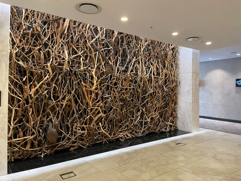 A modern, well-maintained hallway featuring polished marble flooring and a large, intricate decorative feature wall with integrated recessed lighting.