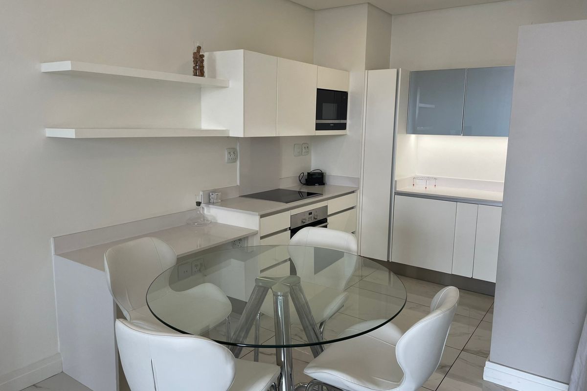 Modern kitchen featuring white cabinetry, stone countertops, integrated appliances, and sleek tiled flooring, offering a clean and functional culinary space.