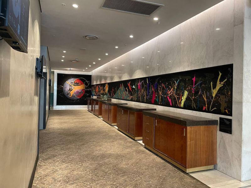 A sophisticated, well-lit hallway featuring marble wall cladding, integrated wooden cabinetry with stone countertops, and high-quality finishes throughout.