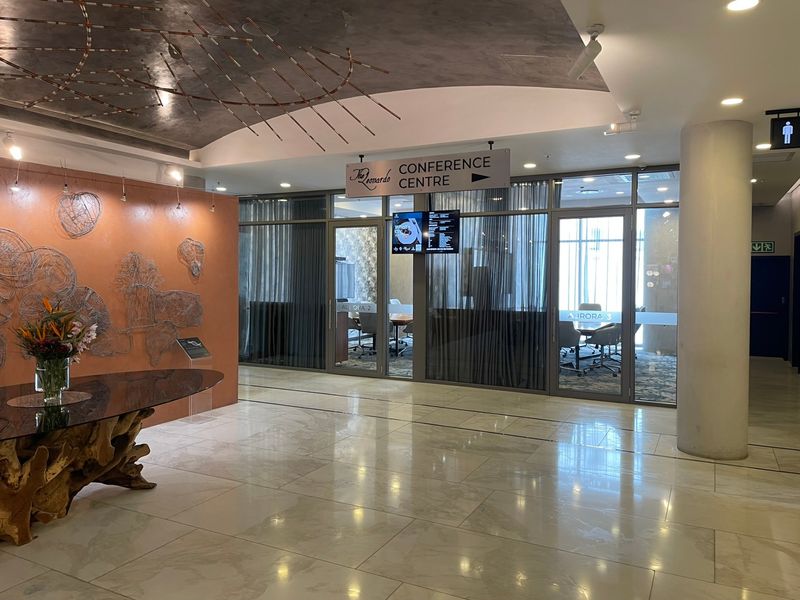 Modern conference centre entrance featuring polished marble flooring, glass-partitioned meeting rooms, and contemporary architectural ceiling details.
