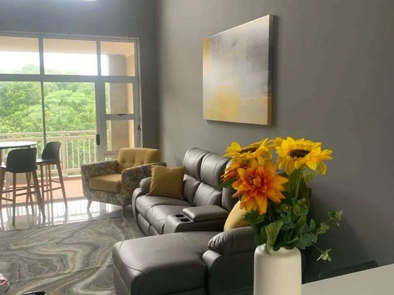 Spacious open-plan living area featuring high ceilings, crown molding, and large glass sliding doors that provide ample natural light and access to the balcony.