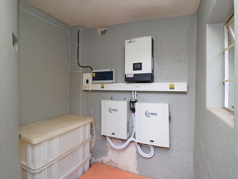 Utility space featuring a solar inverter and dual lithium-ion battery storage system for backup power.