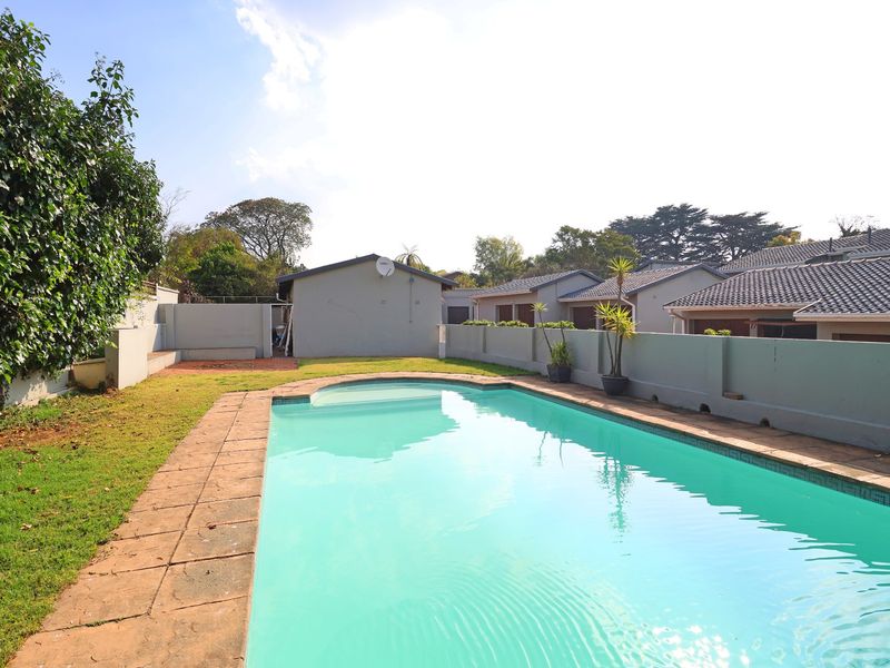 A private outdoor pool area featuring a swimming pool, paved surround, and perimeter walling within a townhouse complex setting.