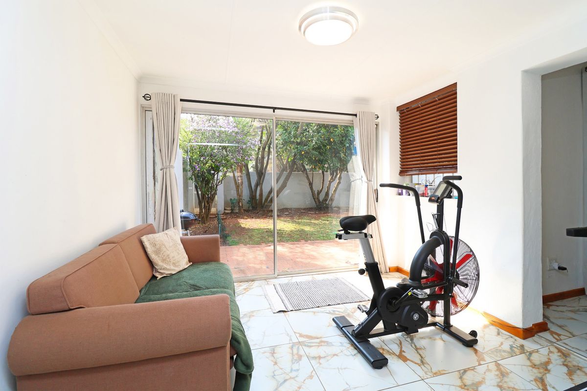 A bright living area featuring marble-look floor tiles and a large sliding glass door providing direct access to the garden.