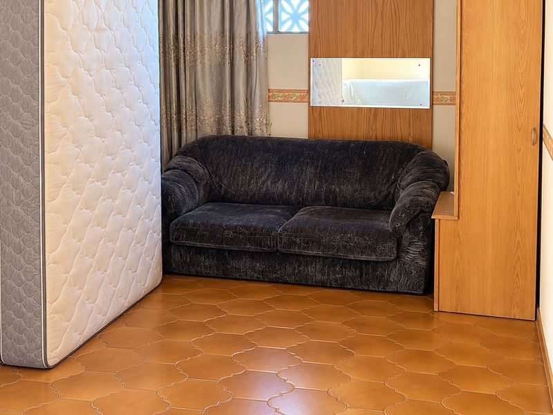 A bedroom featuring decorative breeze block windows and ceramic floor tiles, offering a functional space with built-in wall paneling.