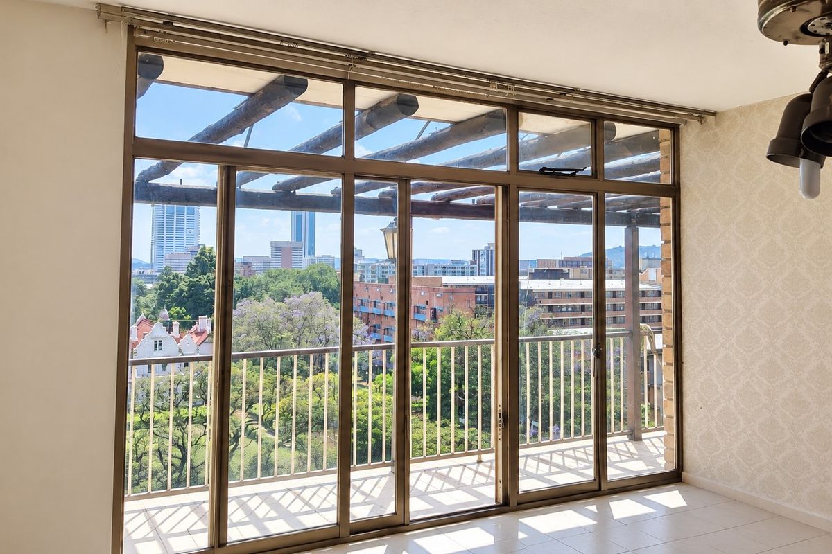 Bright living area featuring large sliding glass doors that open onto a balcony with expansive city views and tiled flooring throughout.