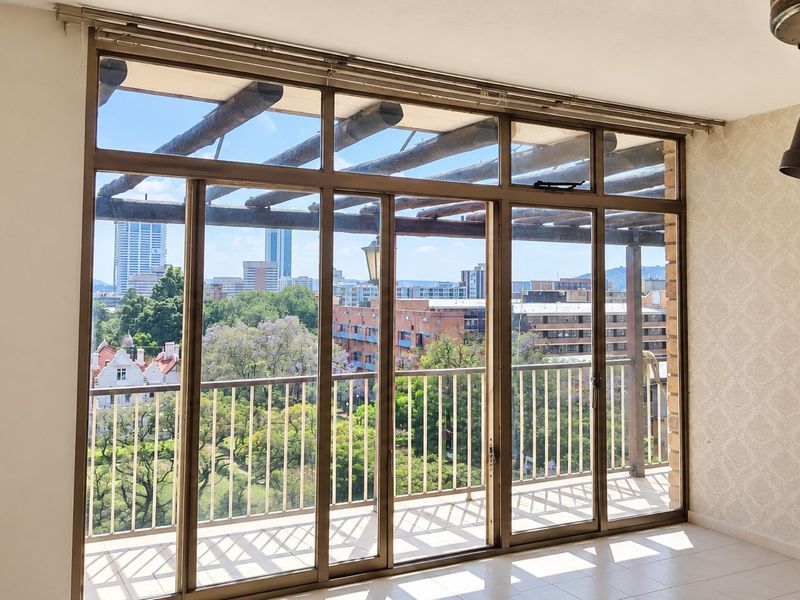 Bright living area featuring large sliding glass doors that open onto a balcony with expansive city views and tiled flooring throughout.