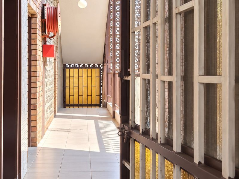 A well-maintained apartment building hallway featuring tiled floors, decorative brick walls, and a functional fire safety hose reel.