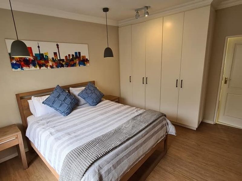 A well-maintained bedroom featuring neutral walls, laminate flooring, and ample built-in cupboard storage.