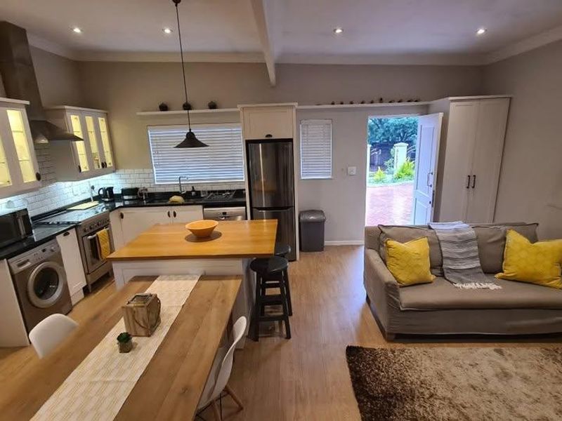 Open-plan kitchen and living area featuring modern cabinetry, a central island, subway tile backsplash, and direct access to the rear exterior.
