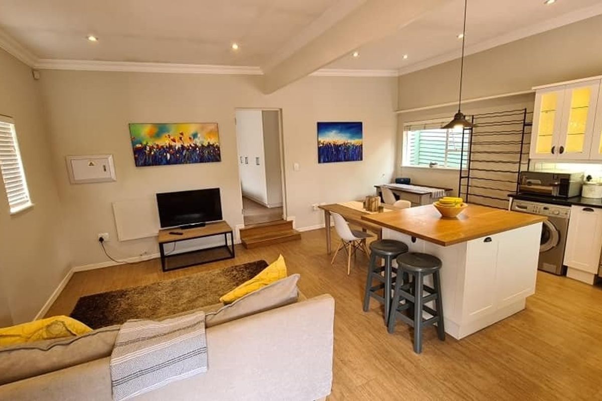 An open-plan living and kitchen area featuring a central island, modern cabinetry, subway tile backsplash, and recessed lighting throughout.