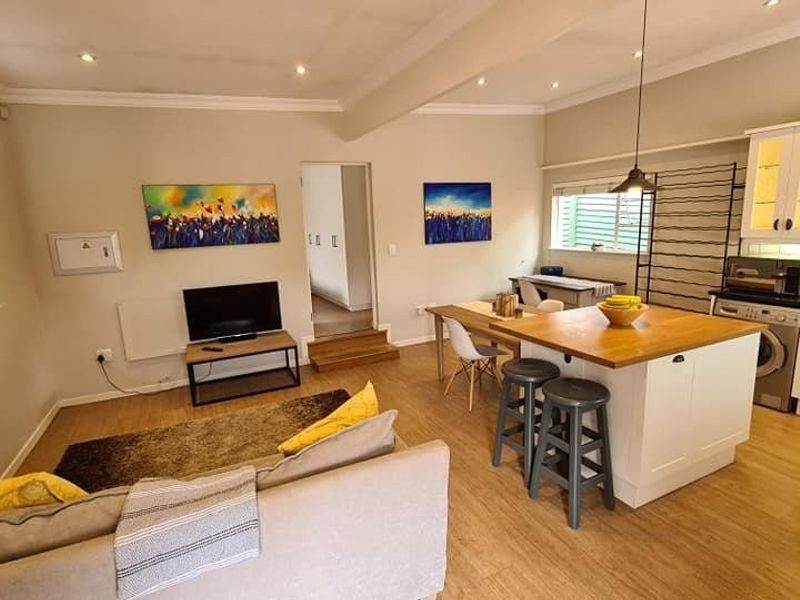 An open-plan living and kitchen area featuring a central island, modern cabinetry, subway tile backsplash, and recessed lighting throughout.