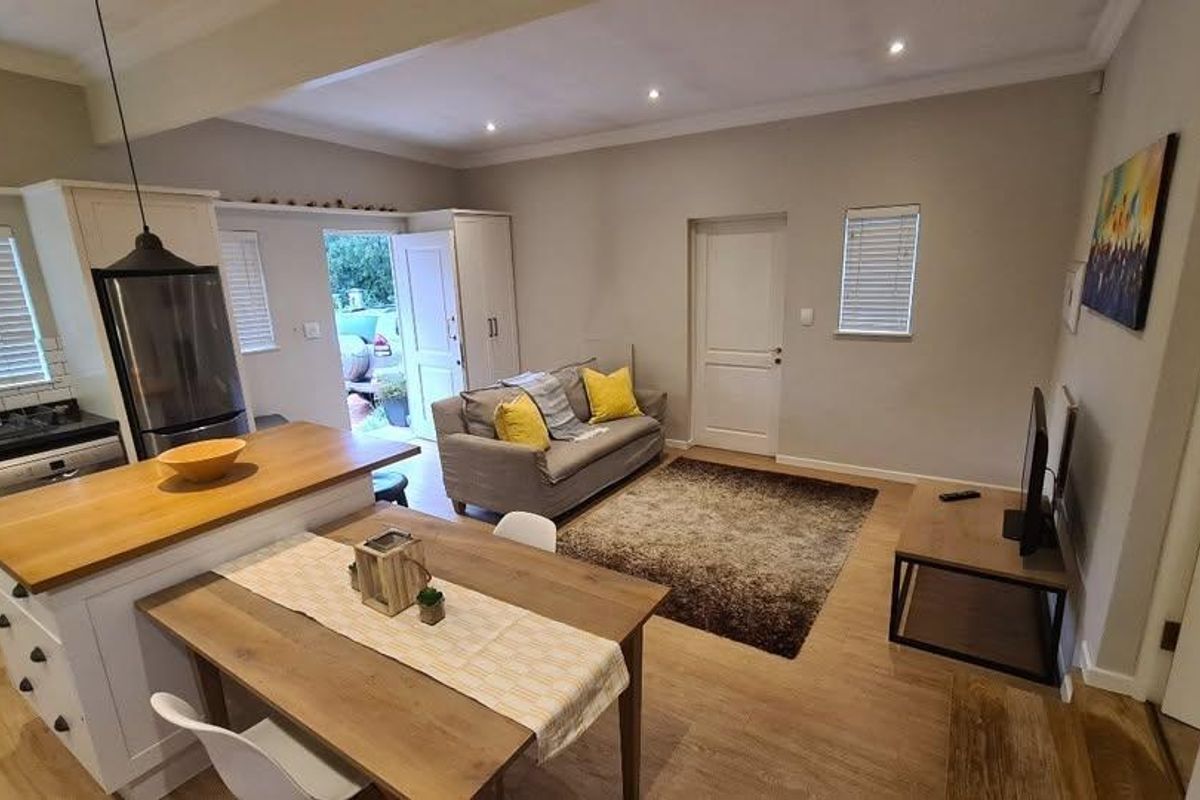 An open-plan living and kitchen area featuring a central island with a wooden countertop, modern cabinetry, and laminate flooring throughout.