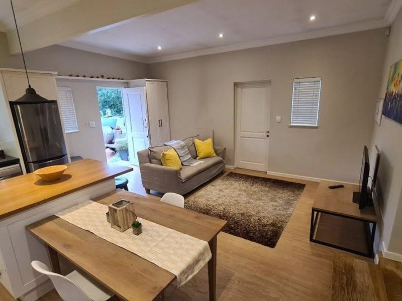 An open-plan living and kitchen area featuring a central island with a wooden countertop, modern cabinetry, and laminate flooring throughout.