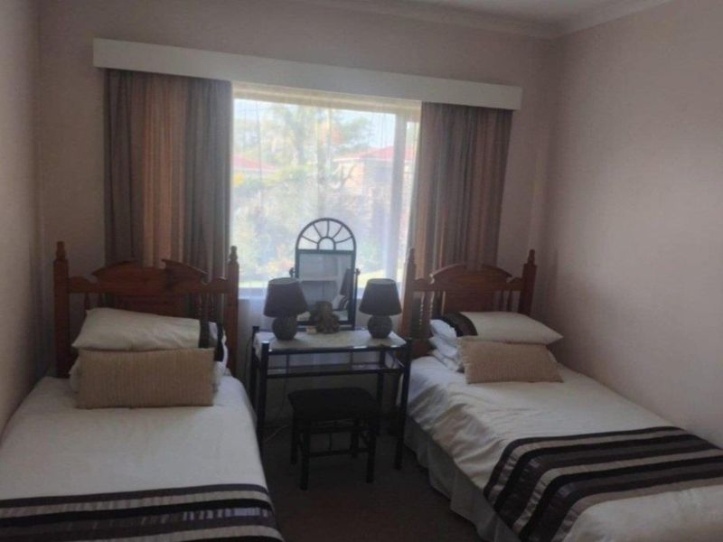 A standard bedroom featuring a large window with natural light and neutral wall finishes.