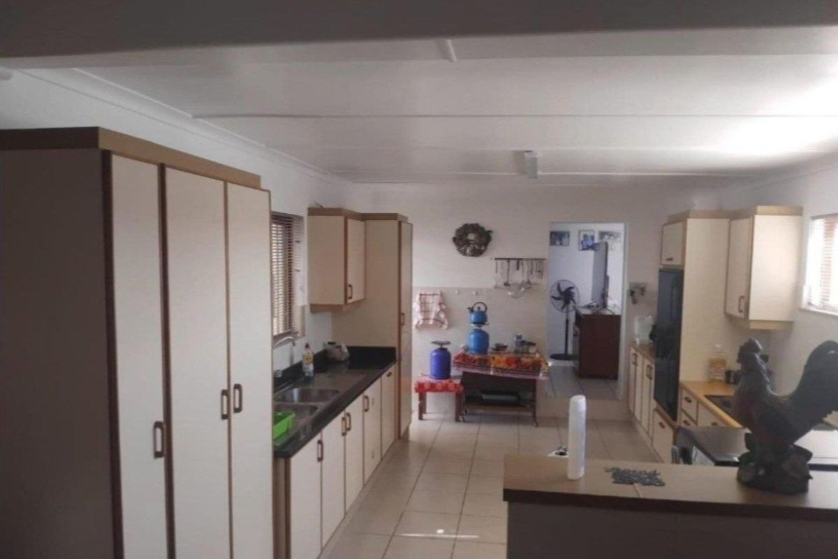 A functional kitchen featuring ample built-in cabinetry, laminate countertops, and tiled flooring, offering a practical layout for daily meal preparation.