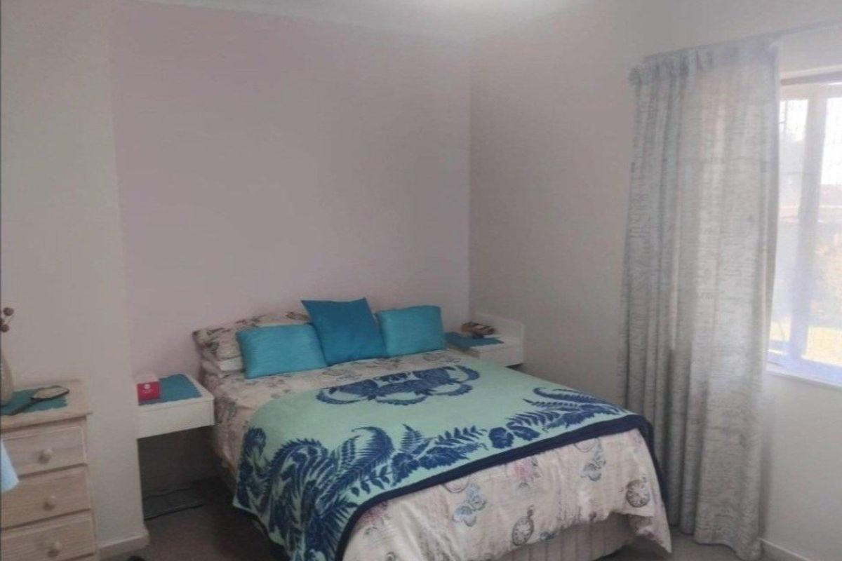 A standard bedroom featuring neutral wall finishes, a window with curtains, and built-in bedside tables.