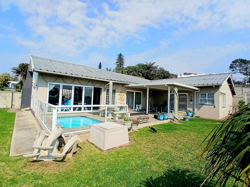 Rear exterior view of the house featuring a swimming pool, covered patio area, and direct access through large glass sliding doors.