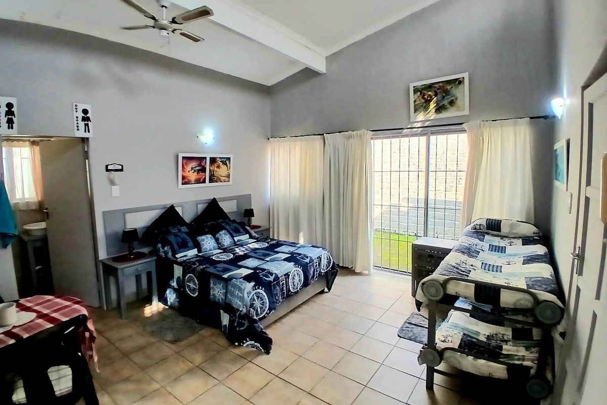Spacious bedroom featuring vaulted ceilings, a ceiling fan, tiled flooring, and a sliding glass door providing direct access to the outdoor area.