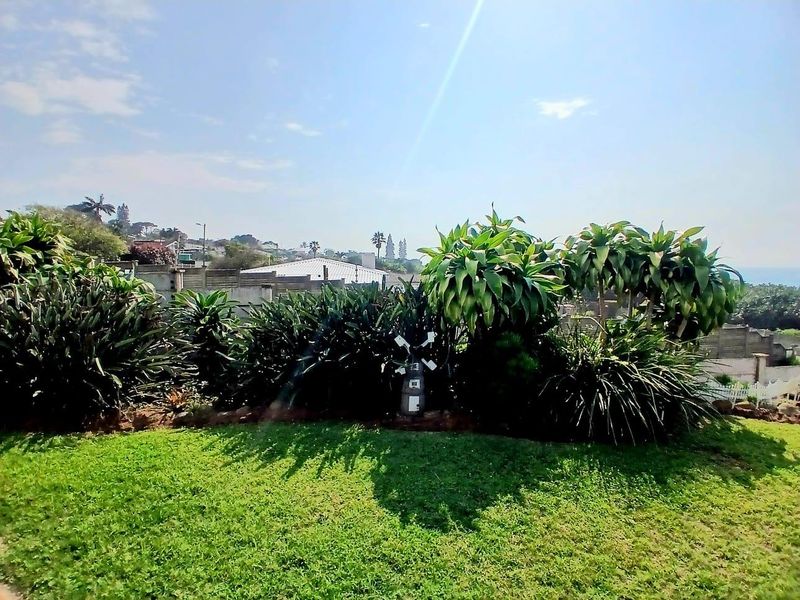 A view of the property's landscaped garden area featuring established greenery and a boundary wall under a clear sky.
