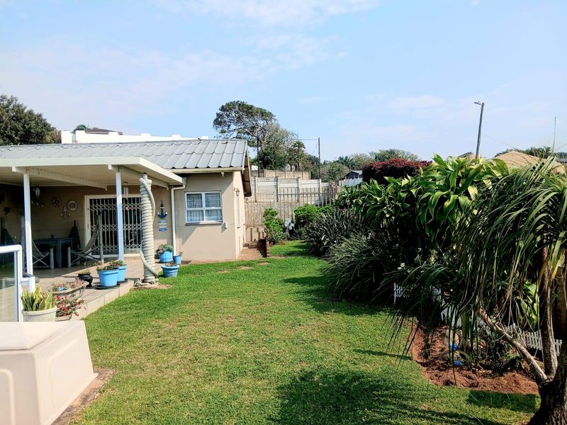 A well-maintained rear garden featuring a covered patio area, paved pathways, and established landscaping adjacent to the main dwelling.