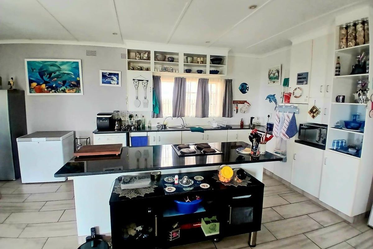 A functional kitchen featuring a central island with a hob, ample built-in cabinetry, tiled flooring, and integrated appliances.