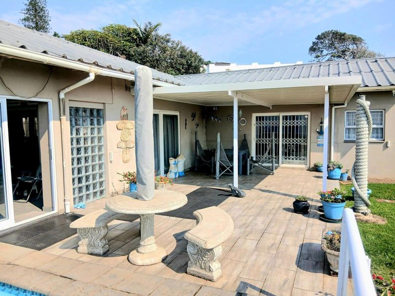 A spacious covered patio area featuring tiled flooring, glass block accents, and sliding door access to the main house interior.