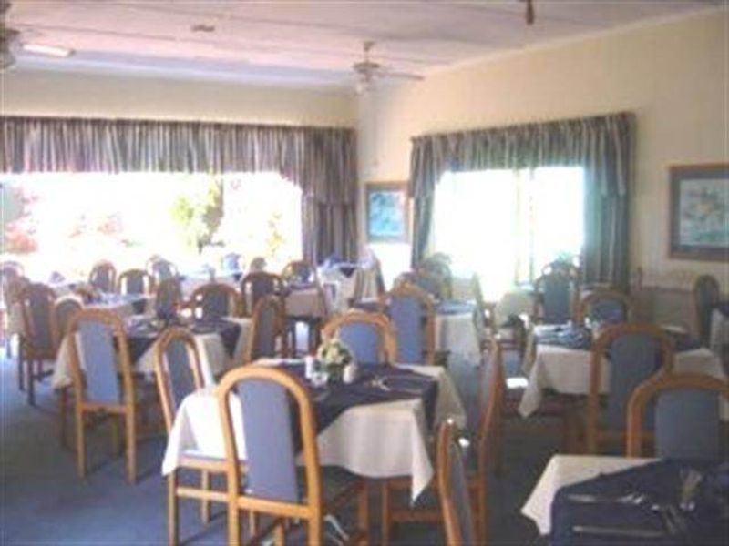 A spacious dining area featuring large windows with curtain rails and ceiling fans, providing a functional space for dining.