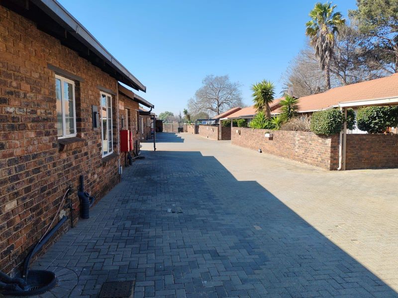 A view of the paved driveway and brick townhouse facades within the complex, featuring well-maintained exterior brickwork and tiled roofing.