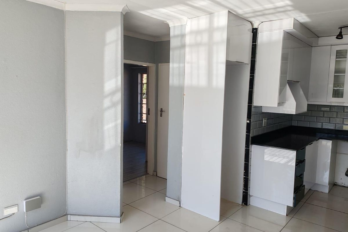 A bright, empty kitchen featuring white cabinetry, black granite countertops, subway tile backsplash, and tiled flooring, ready for final finishing touches.