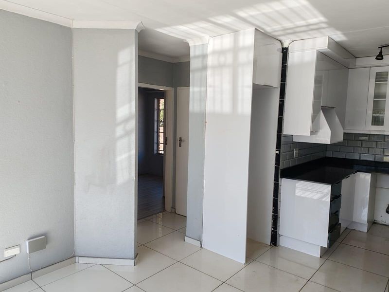 A bright, empty kitchen featuring white cabinetry, black granite countertops, subway tile backsplash, and tiled flooring, ready for final finishing touches.