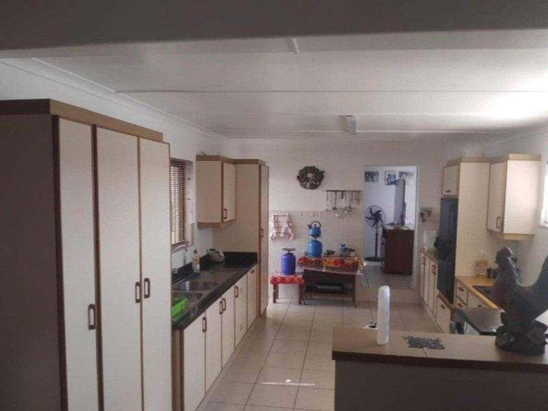A functional kitchen featuring ample built-in cabinetry, laminate countertops, and tiled flooring, offering a practical layout for daily meal preparation.