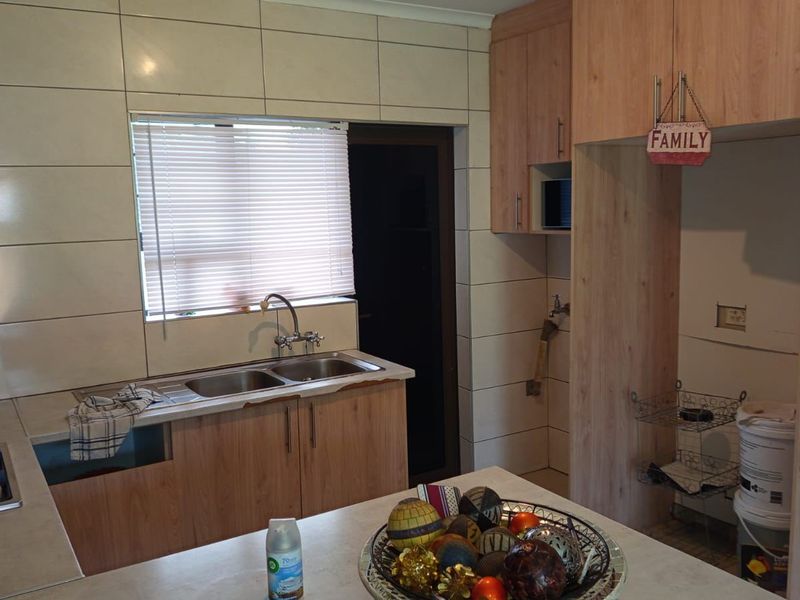 Kitchen featuring light wood-finish cabinetry, a double sink, gas hob with extractor, and tiled splashbacks, with an adjacent utility or appliance nook.