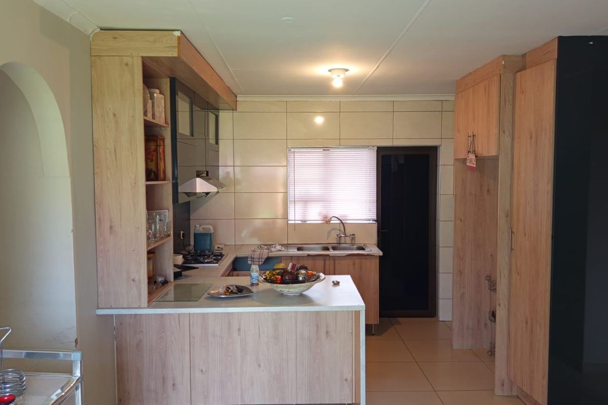 A functional kitchen featuring light wood-look cabinetry, tiled backsplash, double sink, and integrated extractor fan with a breakfast counter.