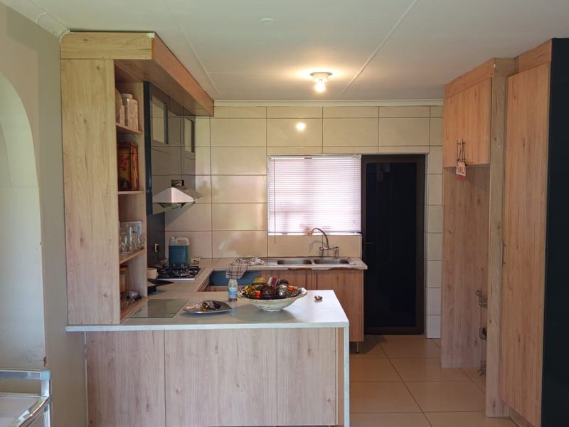 A functional kitchen featuring light wood-look cabinetry, tiled backsplash, double sink, and integrated extractor fan with a breakfast counter.