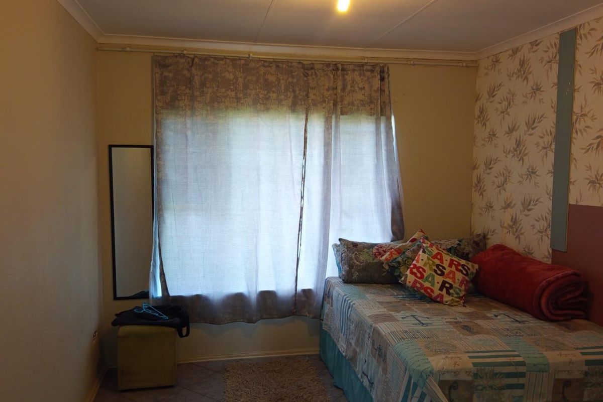 A bedroom featuring tiled flooring and coving, currently requiring cosmetic updates to the wall finishes and wallpaper.
