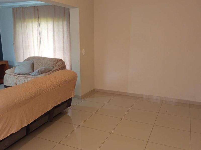A living room area featuring neutral tiled flooring and decorative wall paneling, offering a versatile space for interior design updates.