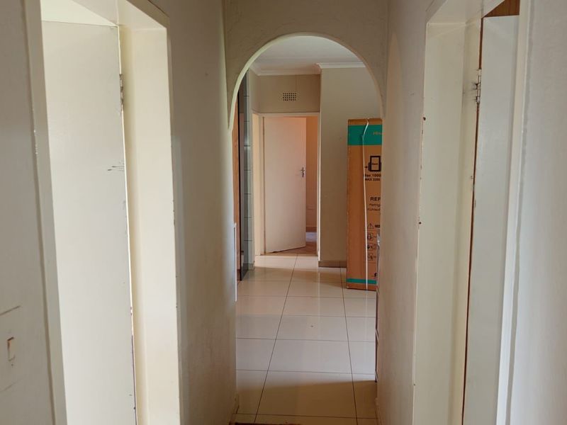 A functional hallway featuring tiled flooring and an arched transition, connecting multiple rooms within the home.