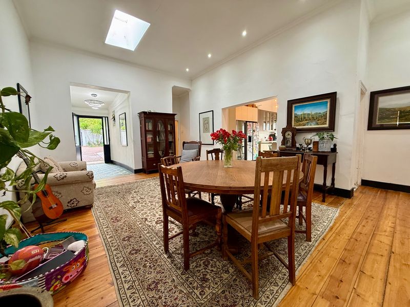 Spacious open-plan dining area featuring polished timber flooring, a skylight, and recessed lighting, with a seamless transition to the kitchen and rear entrance.