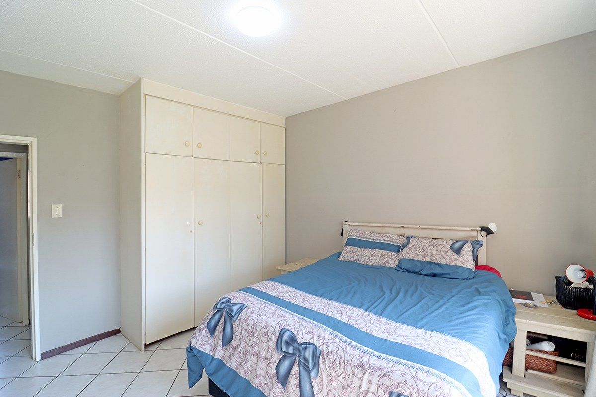 A functional bedroom featuring built-in cupboards, tiled flooring, and neutral wall tones, offering a practical space ready for personal updates.