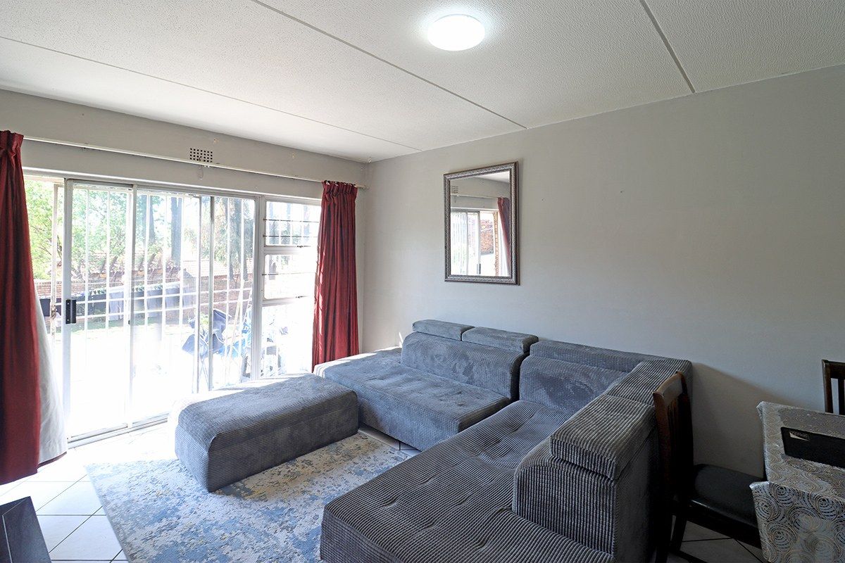 A living room featuring tiled flooring, a flush mount ceiling light, and a large sliding glass door with an integrated security gate.