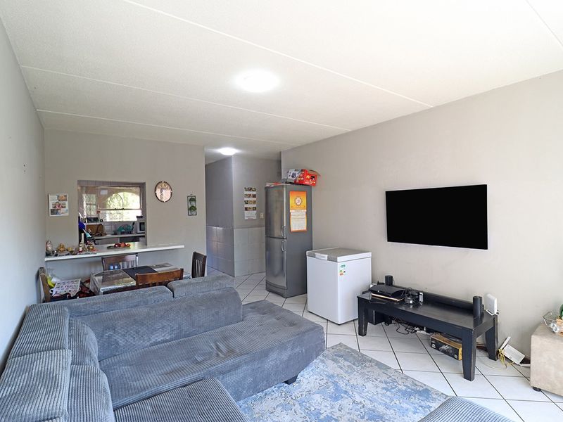 Open-plan living and dining area featuring tiled flooring and a convenient pass-through window connecting to the kitchen space.